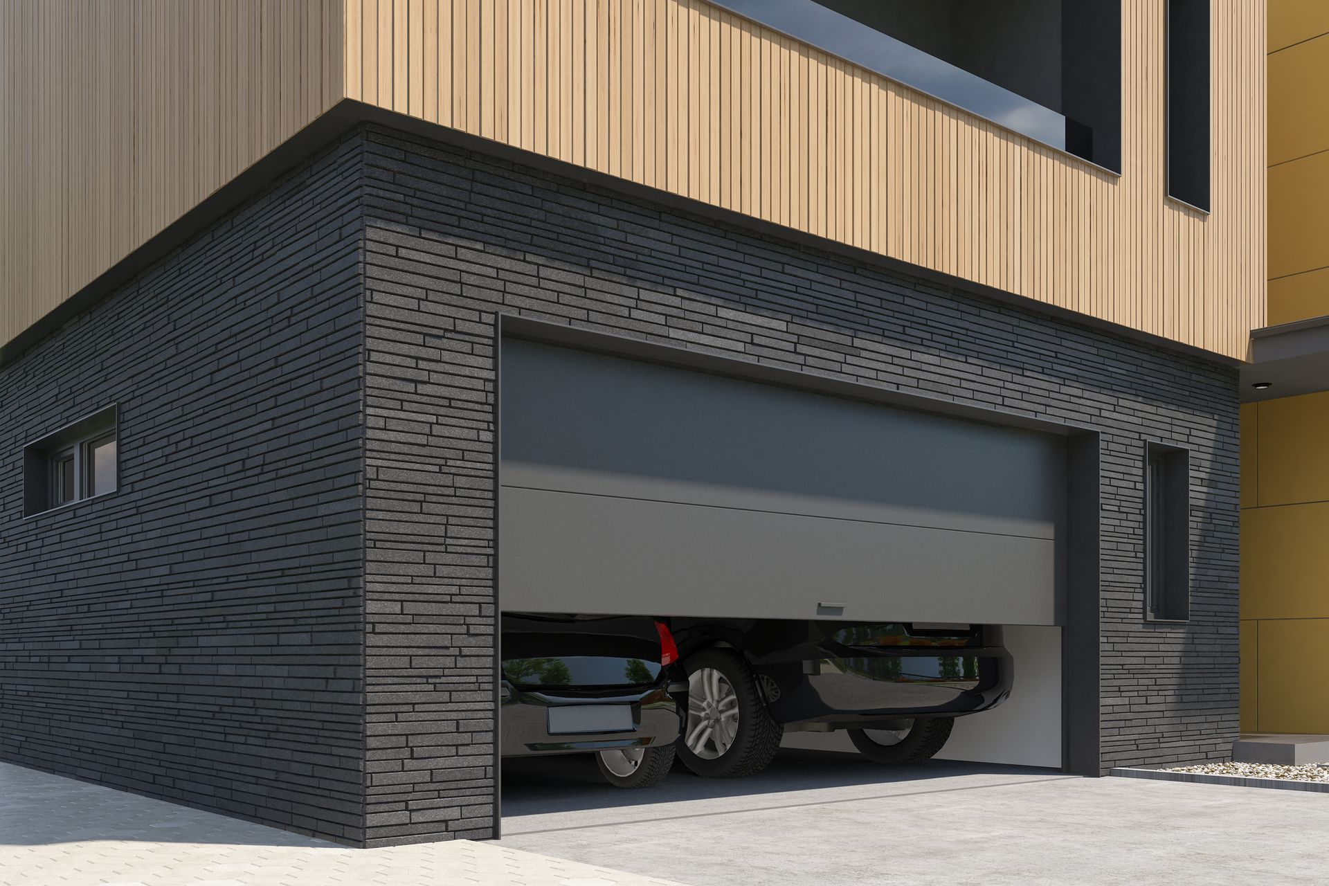 Garage with open gray door, black brick exterior, a car inside, and a wood-paneled building.