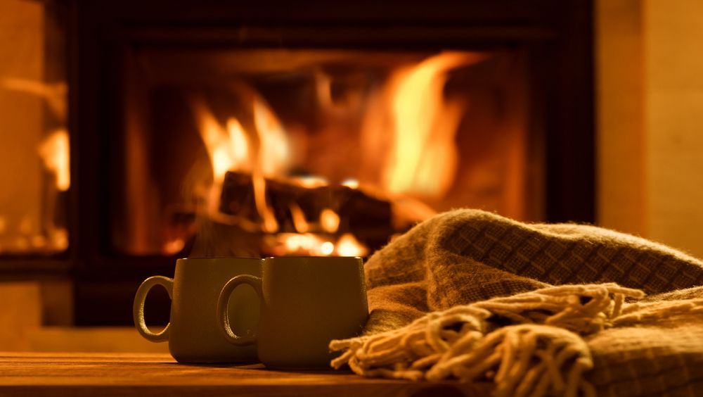 two mugs and blanket in front of fireplace