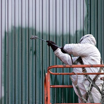 painter in suit spray painting exterior wall