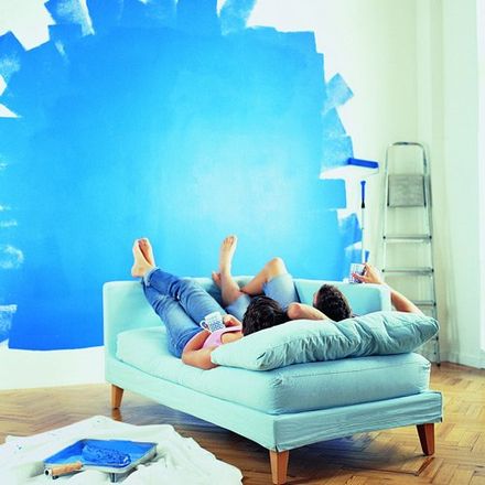 couple laying on sofa looking at painted wall