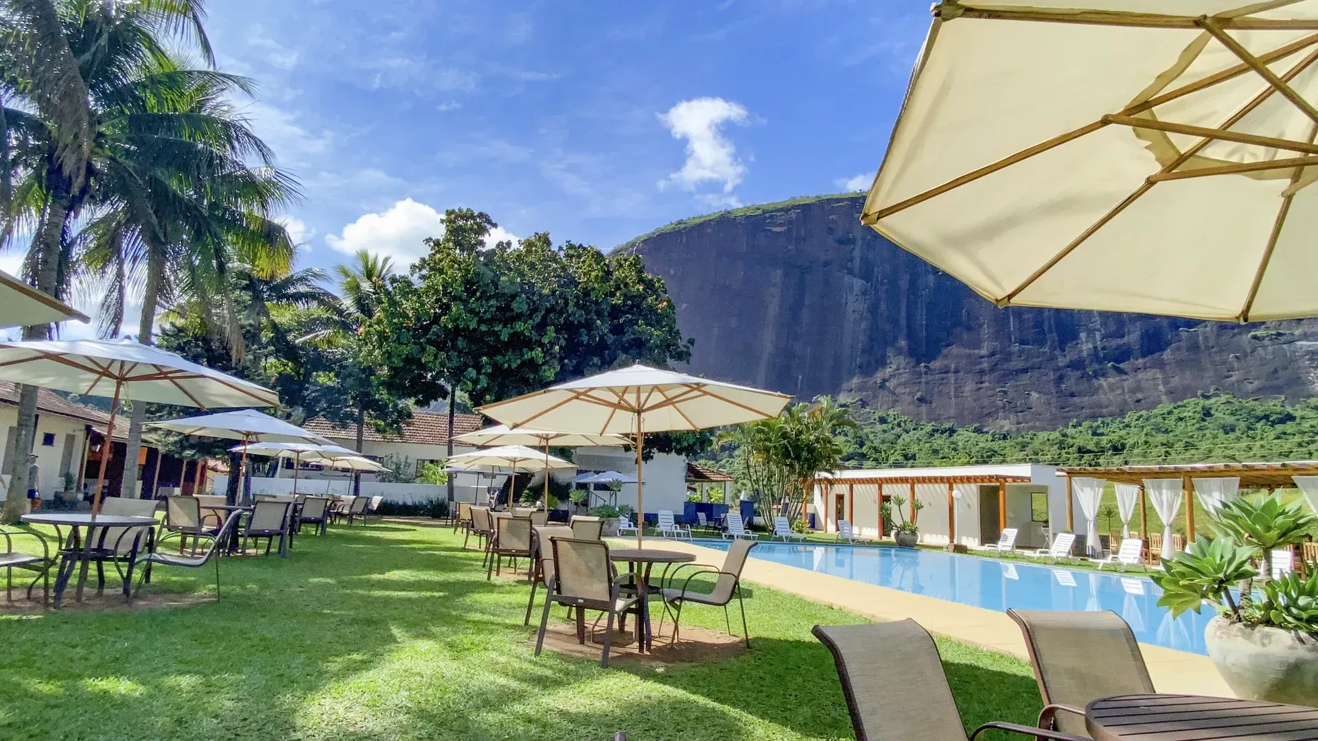 Uma piscina rodeada de mesas e cadeiras com guarda-sóis.