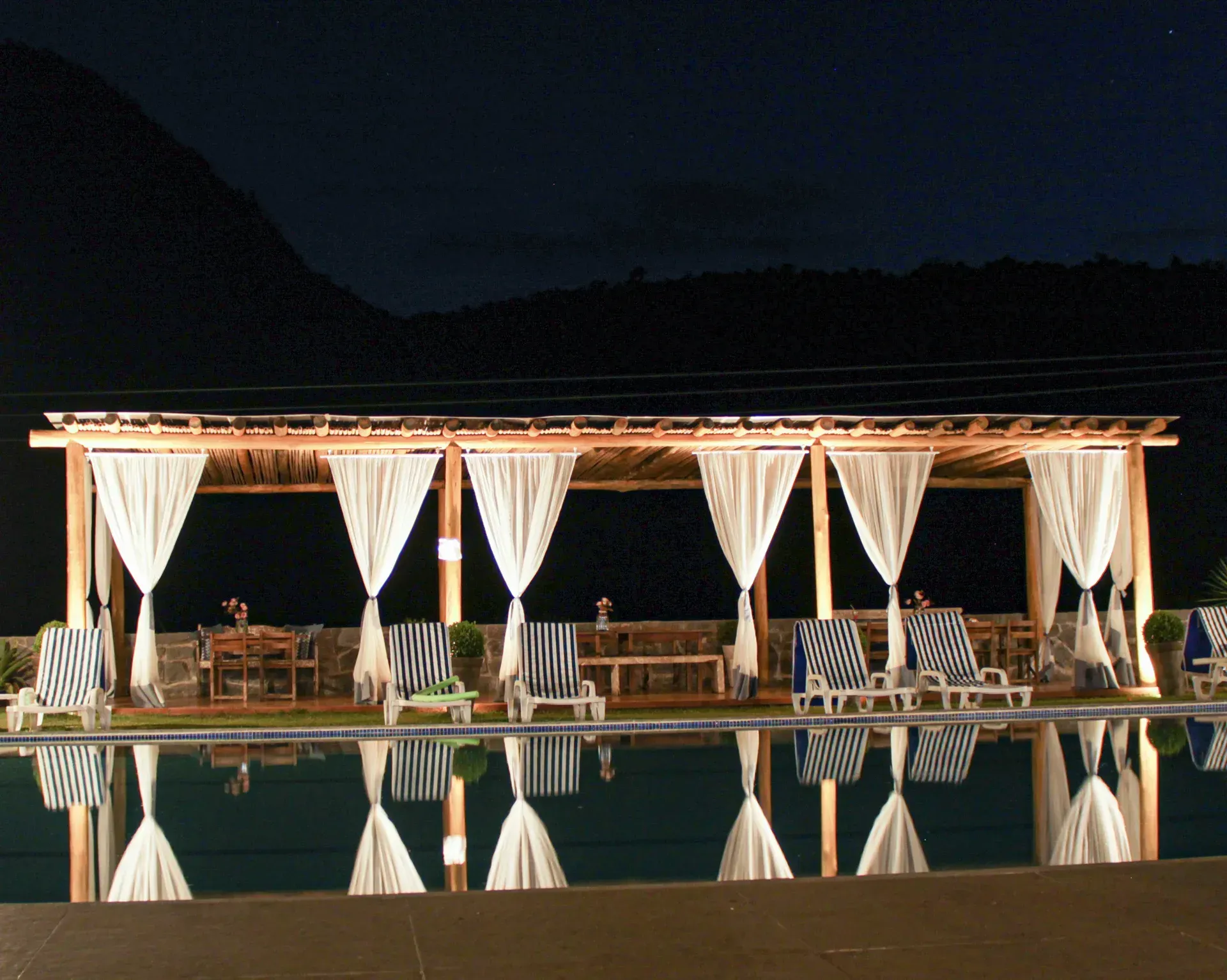 Uma grande piscina é iluminada à noite