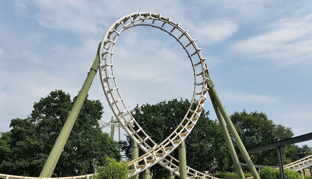 A roller coaster in an amusement park with trees in the background.