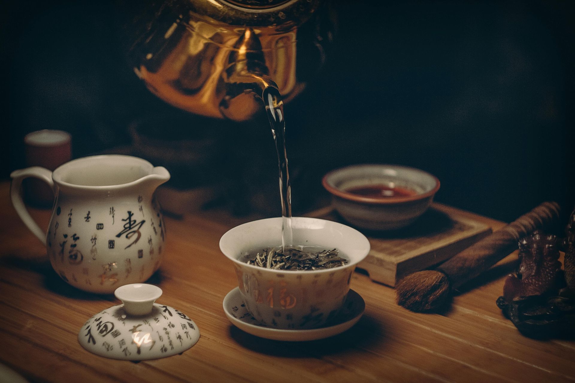 A teapot is pouring tea into a cup on a wooden table.