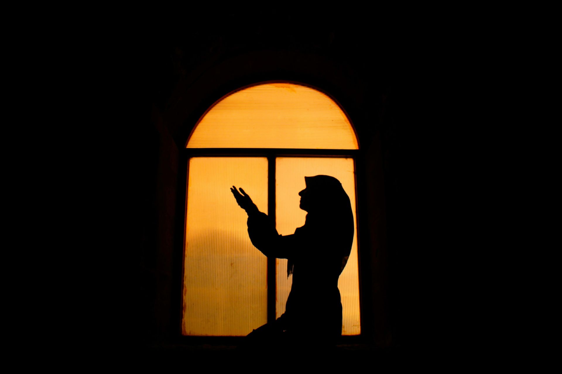 A silhouette of a woman standing in front of a window.