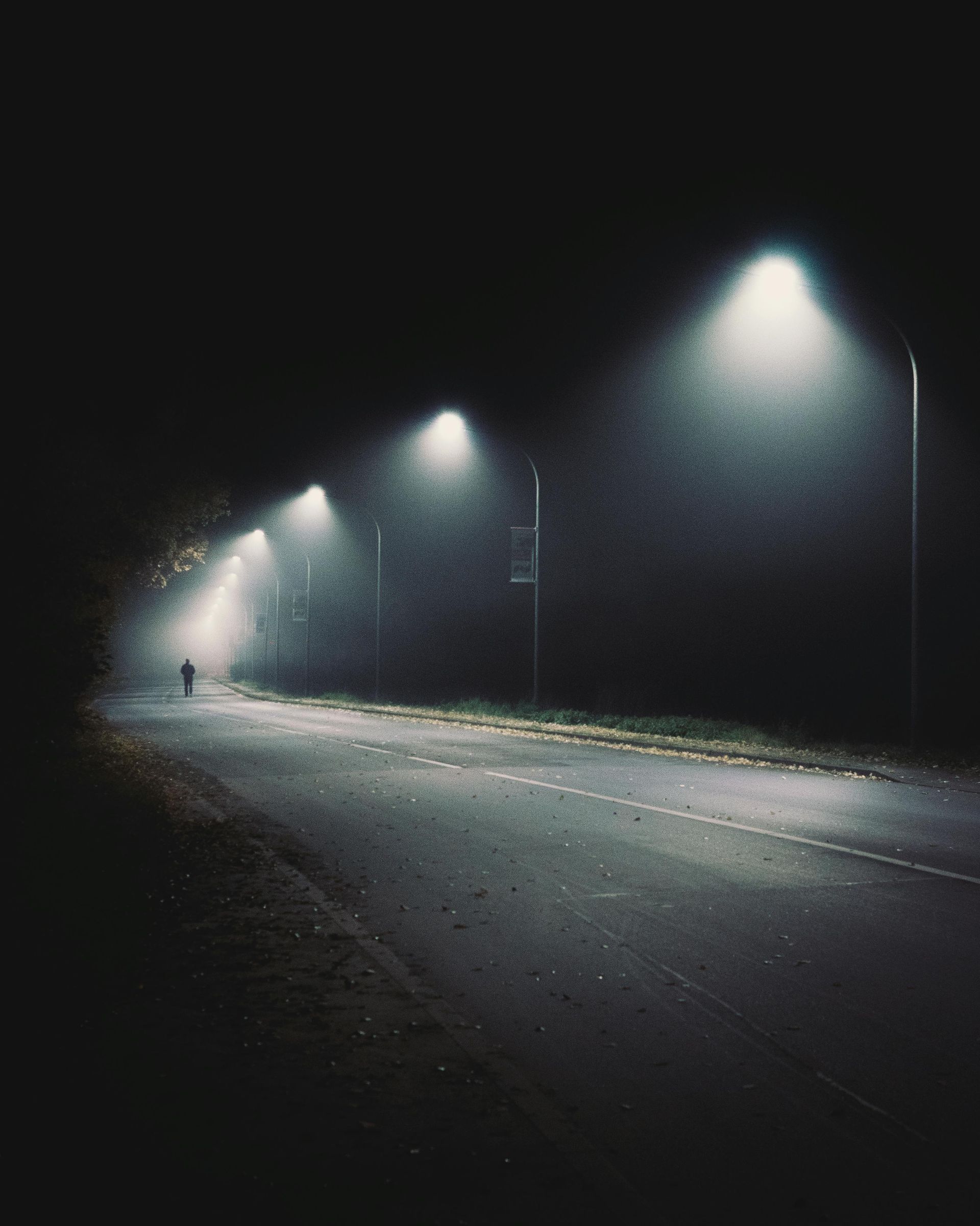A person is walking down a dark street at night.
