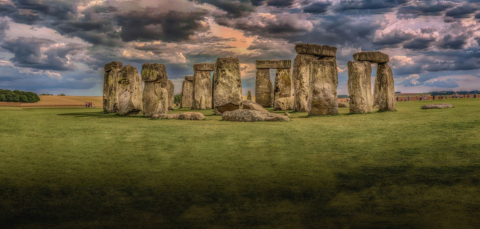 Stonehenge under a cloudy sky, surrounded by a grassy field.