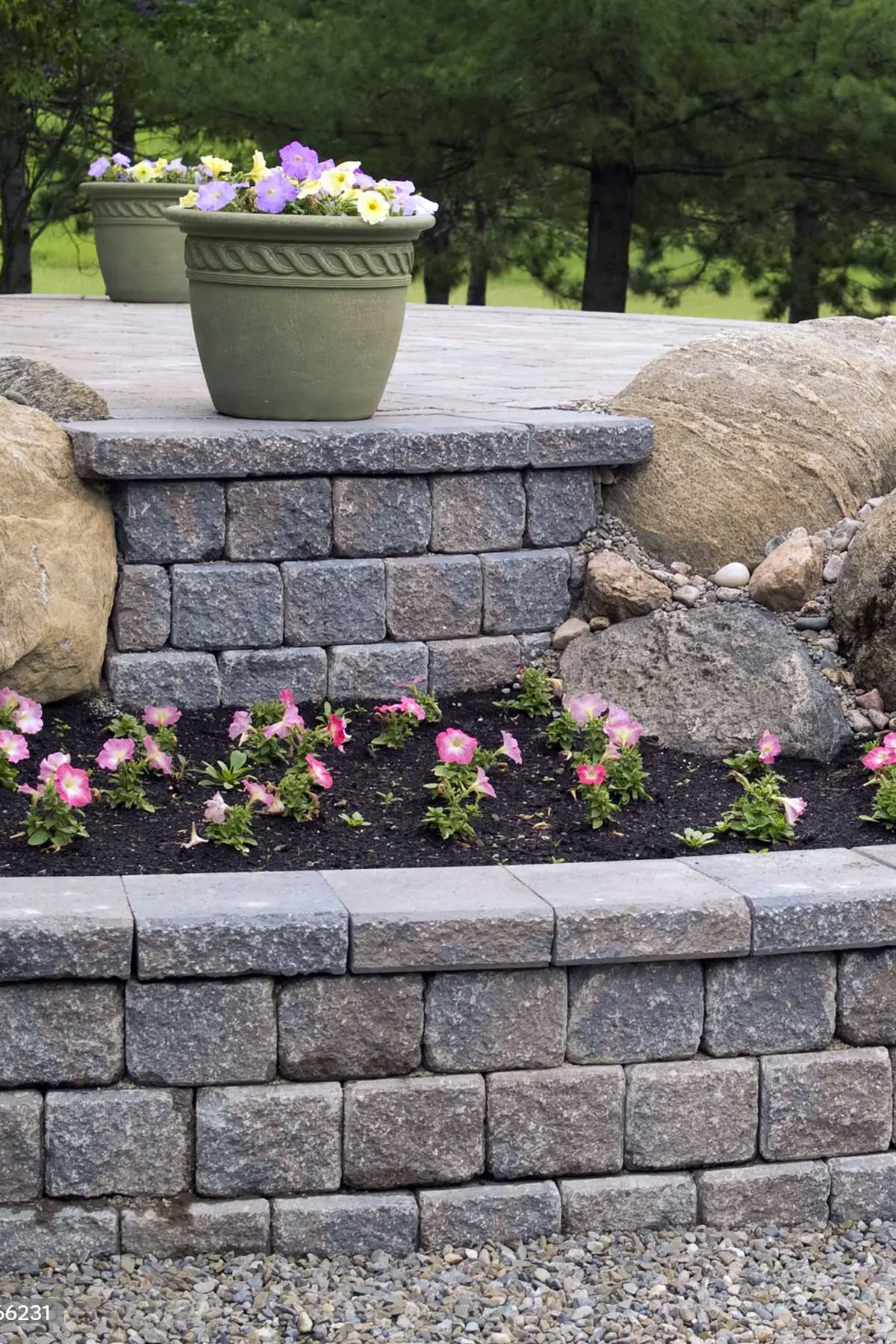 A stone wall with flowers in pots on top of it.
