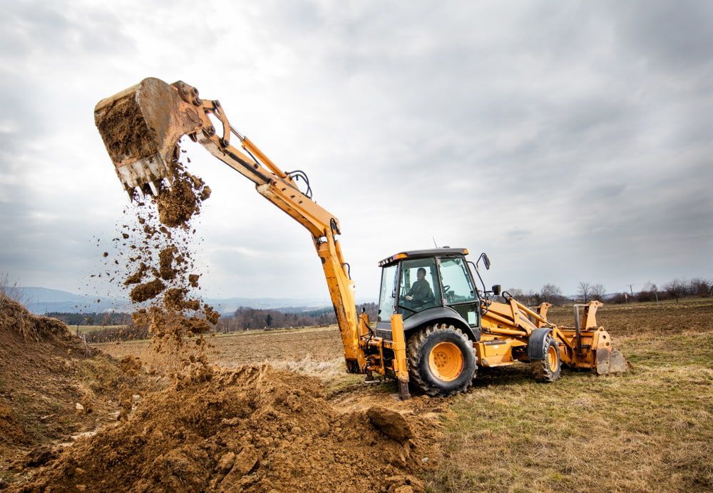 A Bulldozer Is Digging A Hole In A Field — Dubbo Hardcore Soils & Earthmoving In Dubbo, NSW