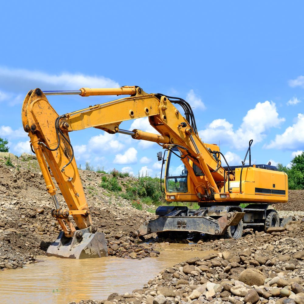 A Yellow Excavator Is Digging A Hole In The Ground — Dubbo Hardcore Soils & Earthmoving In Dubbo, NSW