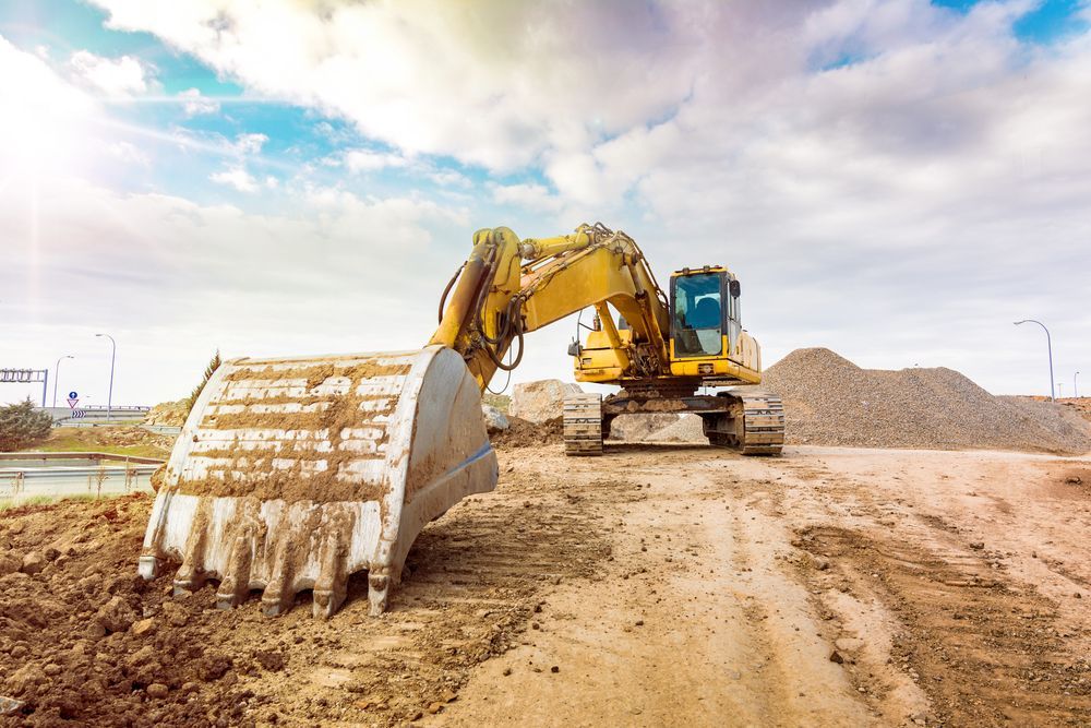 A Yellow Excavator Is Working On A Dirt Road At A Construction Site — Dubbo Hardcore Soils & Earthmoving In Dubbo, NSW