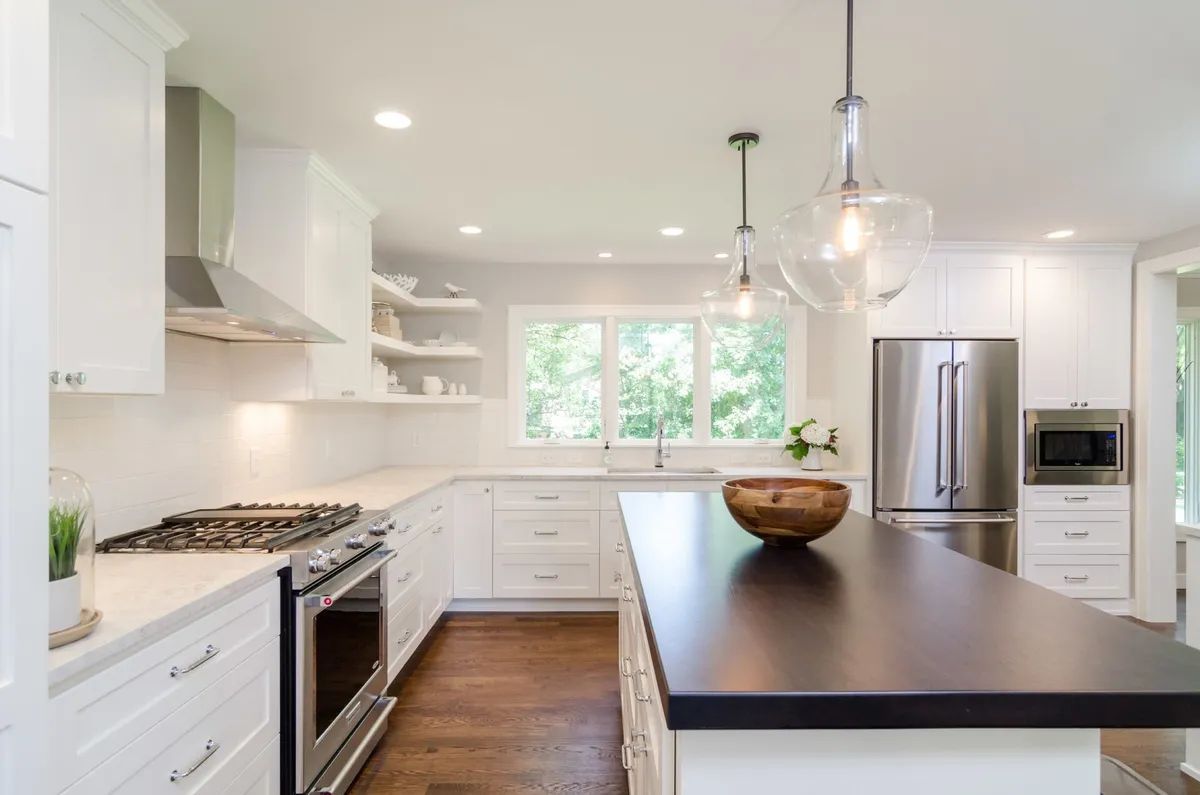A kitchen with white cabinets , stainless steel appliances , and a large island.