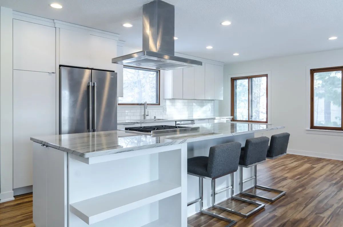 A kitchen with white cabinets , stainless steel appliances and a large island.