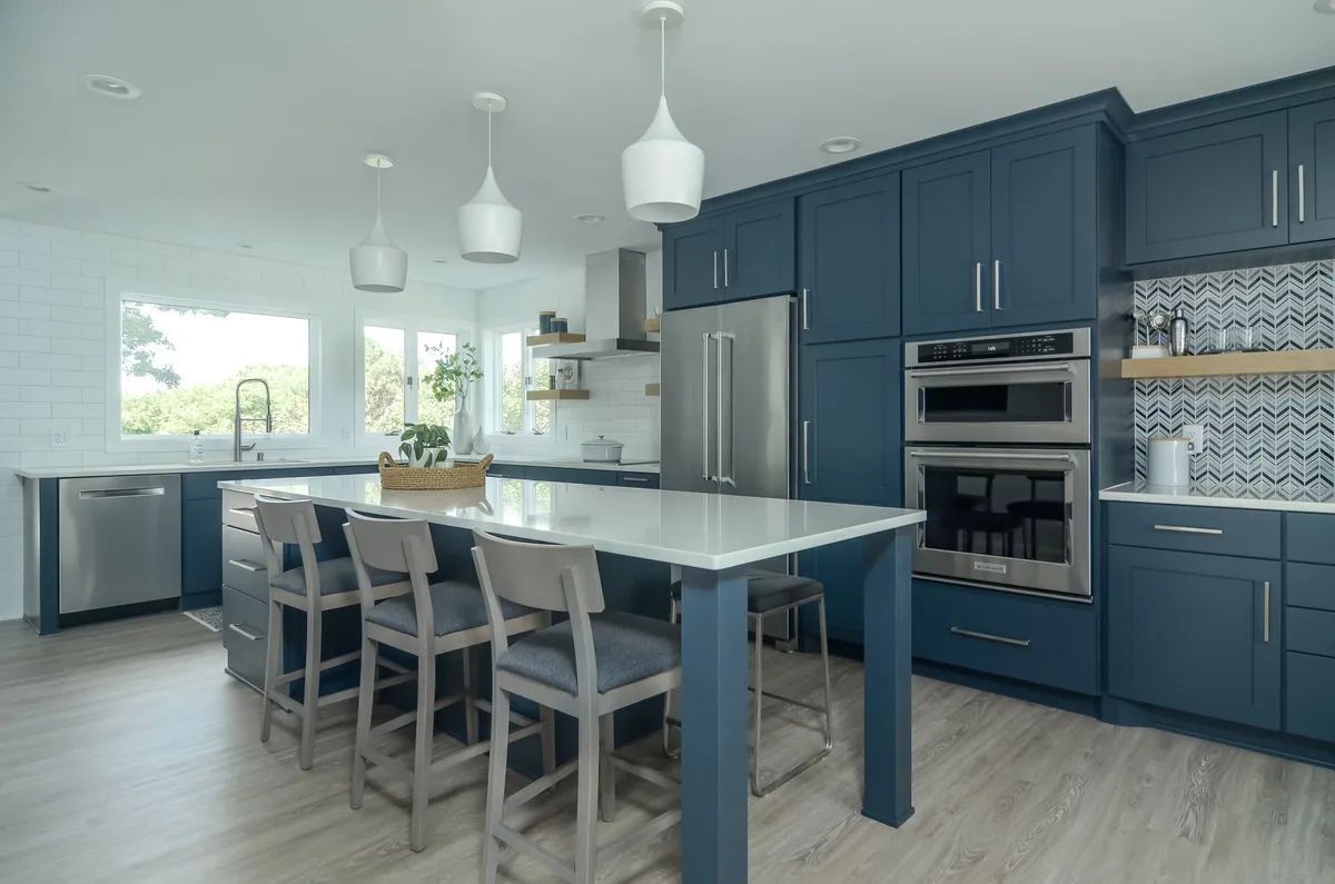 A kitchen with blue cabinets , stainless steel appliances , and a large island.