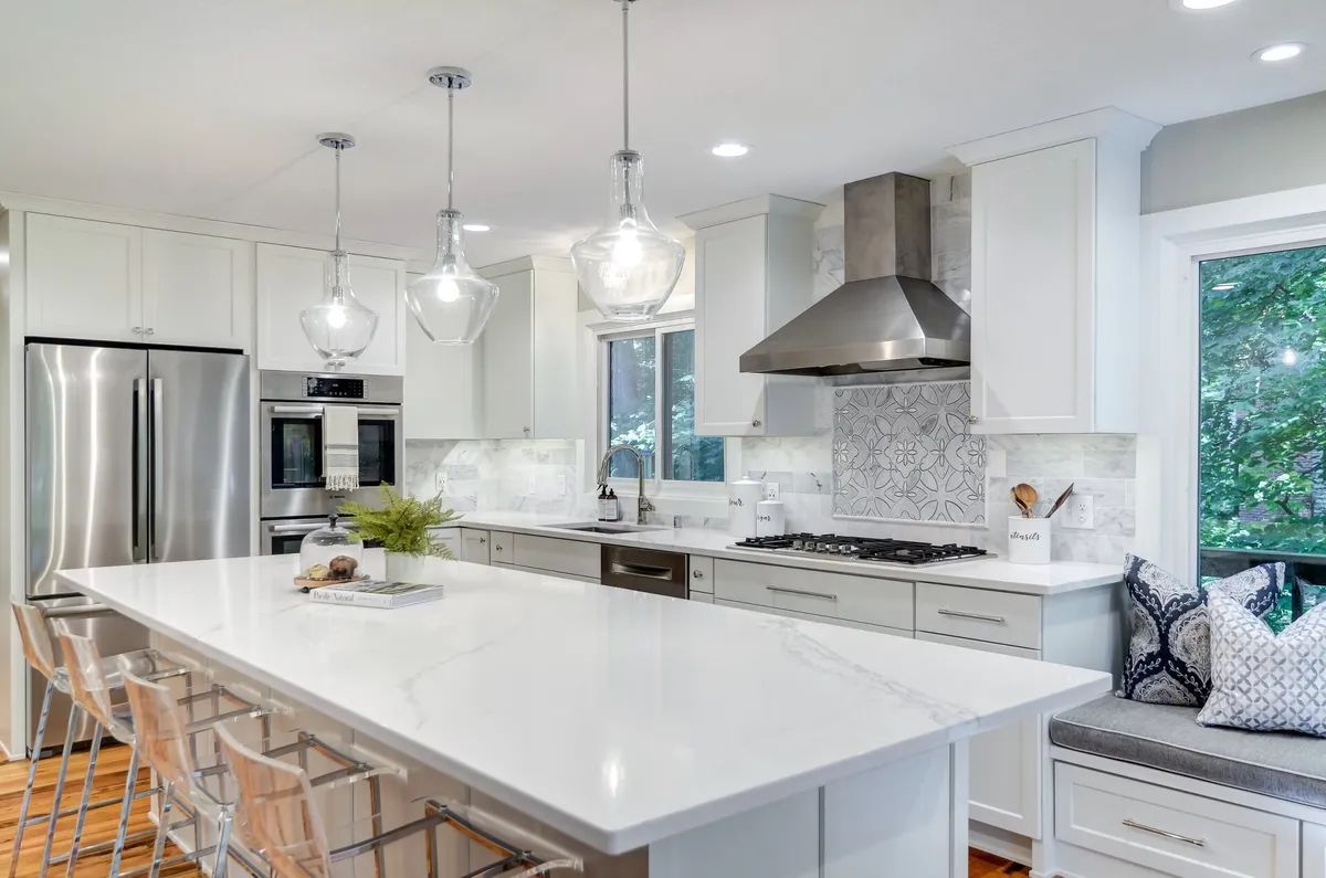 A kitchen with white cabinets , stainless steel appliances , and a large island.