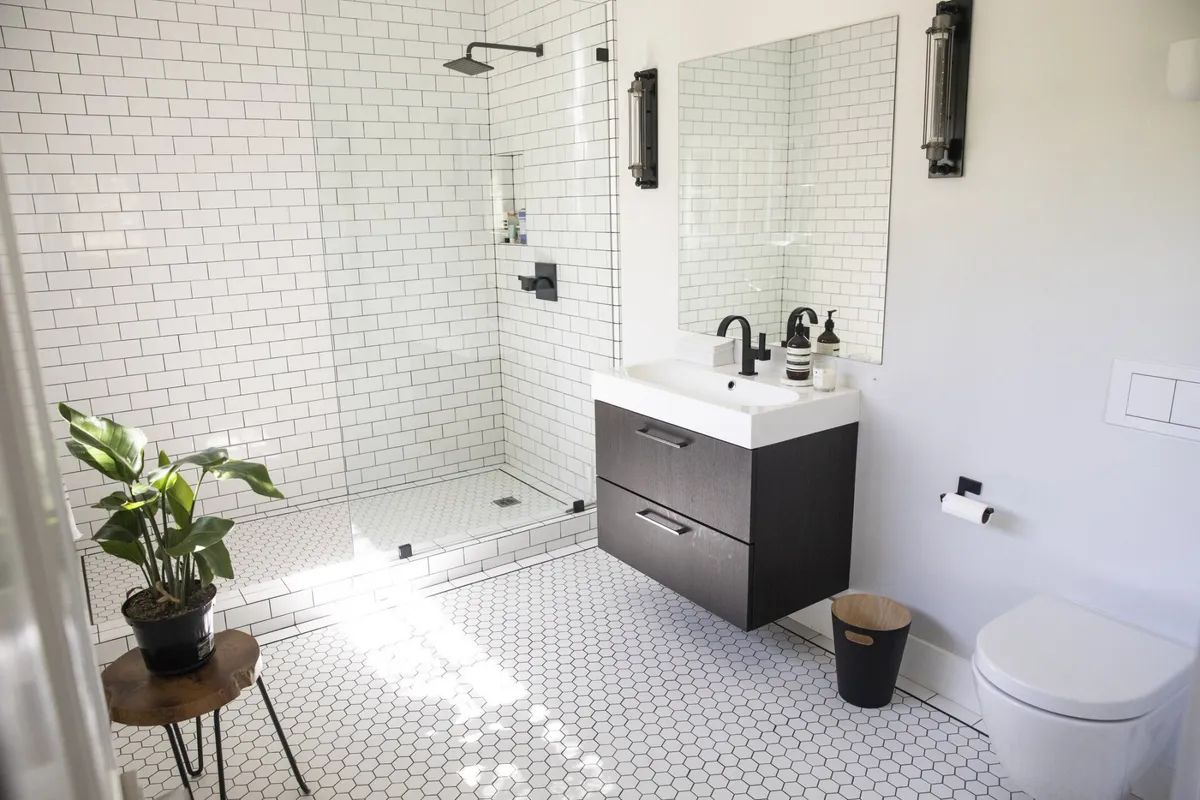 A bathroom with a walk in shower , sink , toilet and mirror.