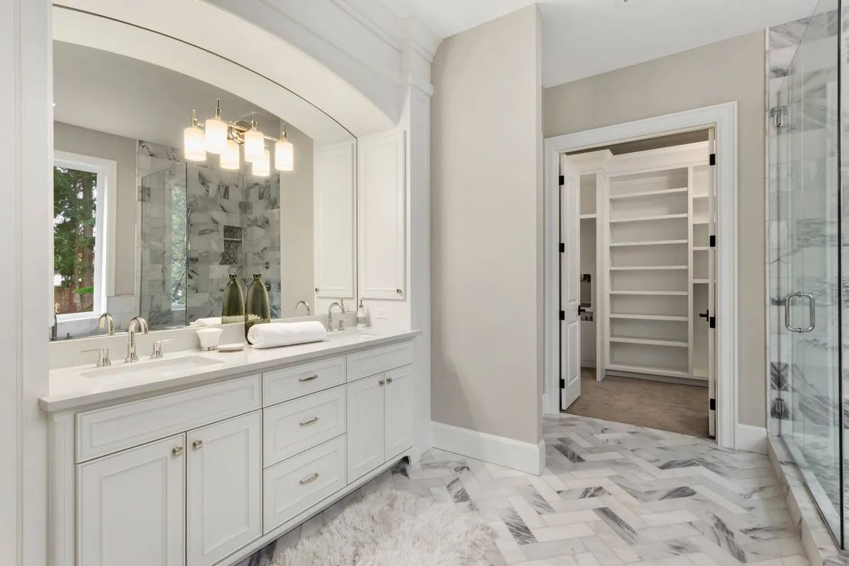 A bathroom with two sinks , a walk in closet and a shower.
