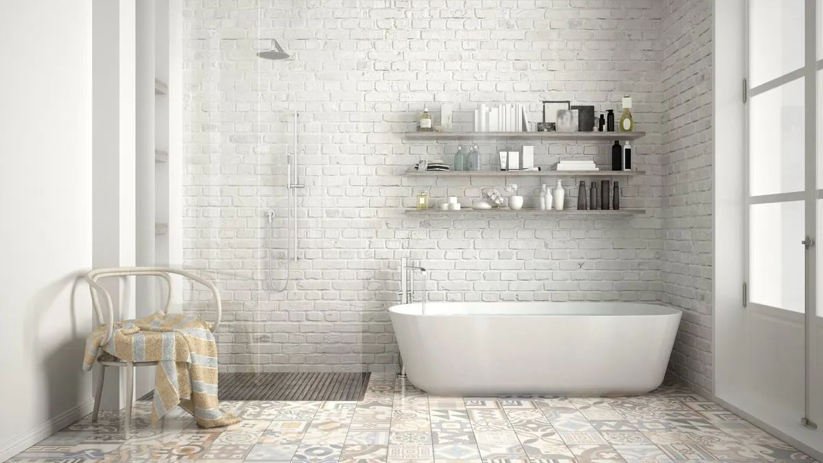 A bathroom with a bathtub , chair , and brick walls.