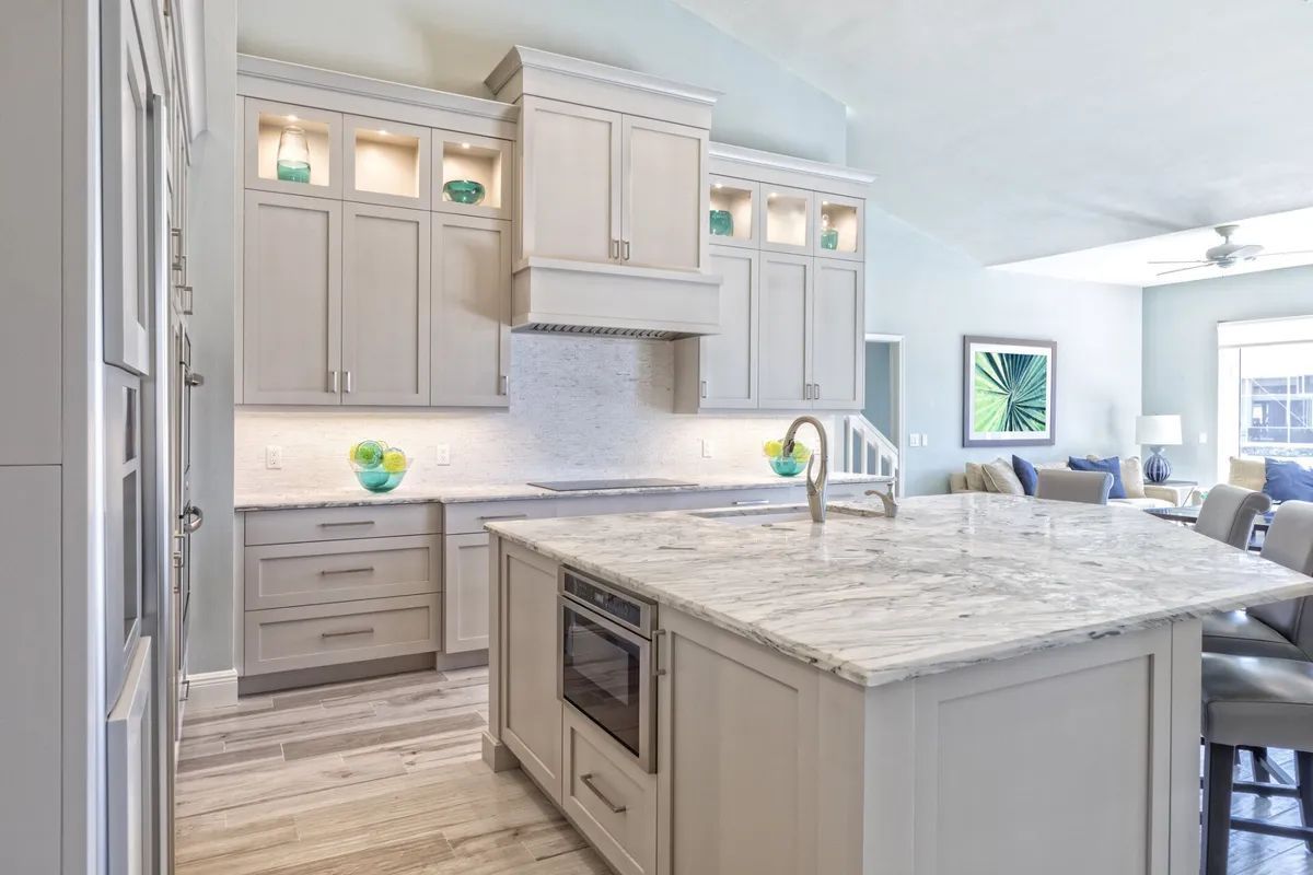 A kitchen with white cabinets , granite counter tops , and a large island.