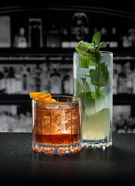 Two drinks are sitting on a table with a bar in the background.