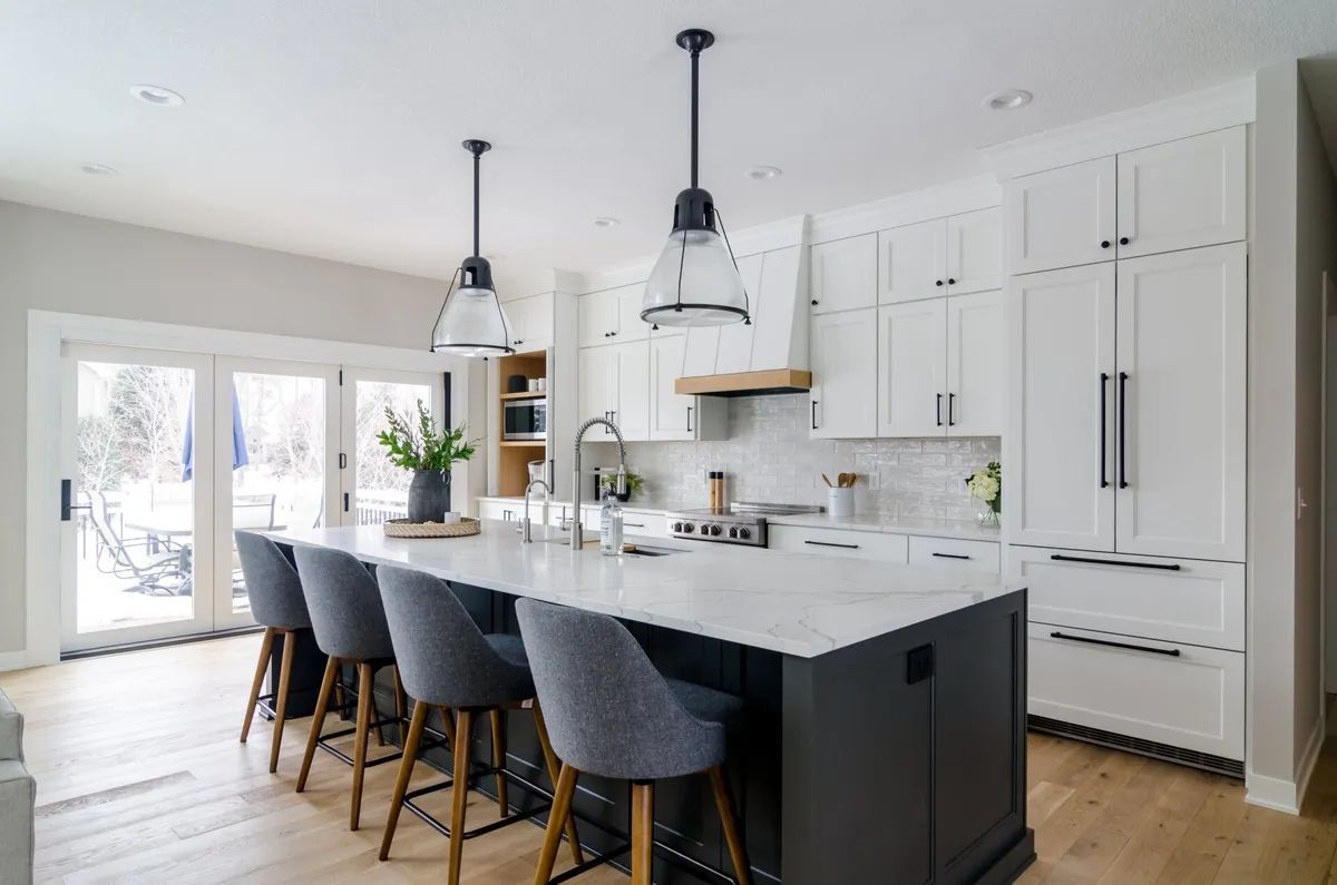 A kitchen with white cabinets and a large island with stools.