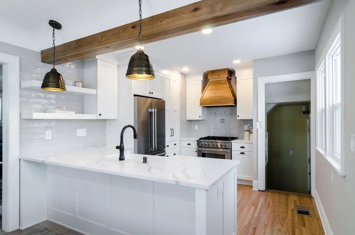 A kitchen with white cabinets , stainless steel appliances , wooden floors and a large island.