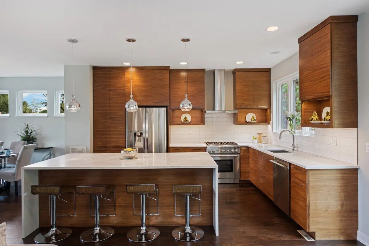 A kitchen with wooden cabinets , white counter tops , stainless steel appliances and a large island.