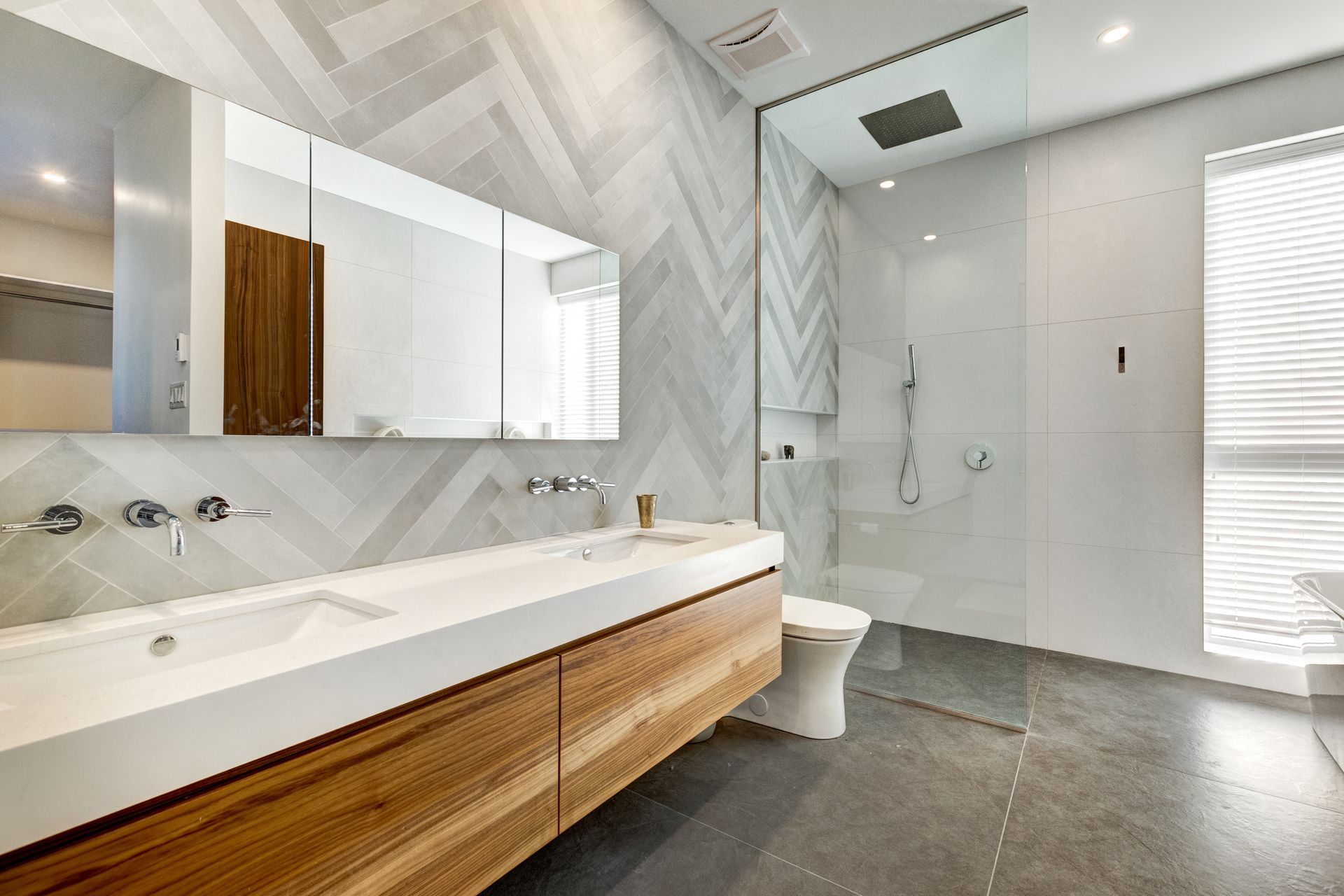 A bathroom with two sinks , a toilet , and a walk in shower.