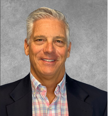 Dick Ren is smiling, wearing a blazer and plaid shirt.