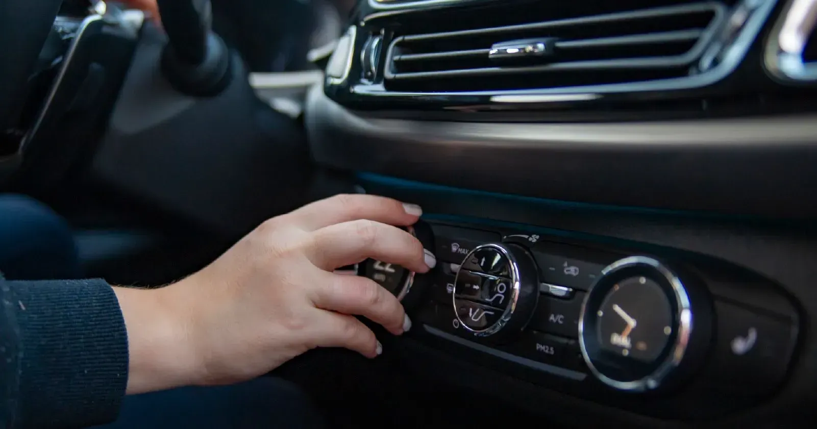 A person is adjusting the air conditioning in a car.