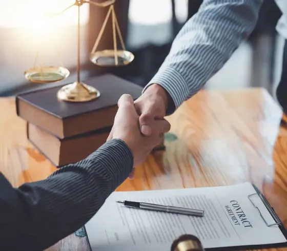 Two men are shaking hands over a contract.