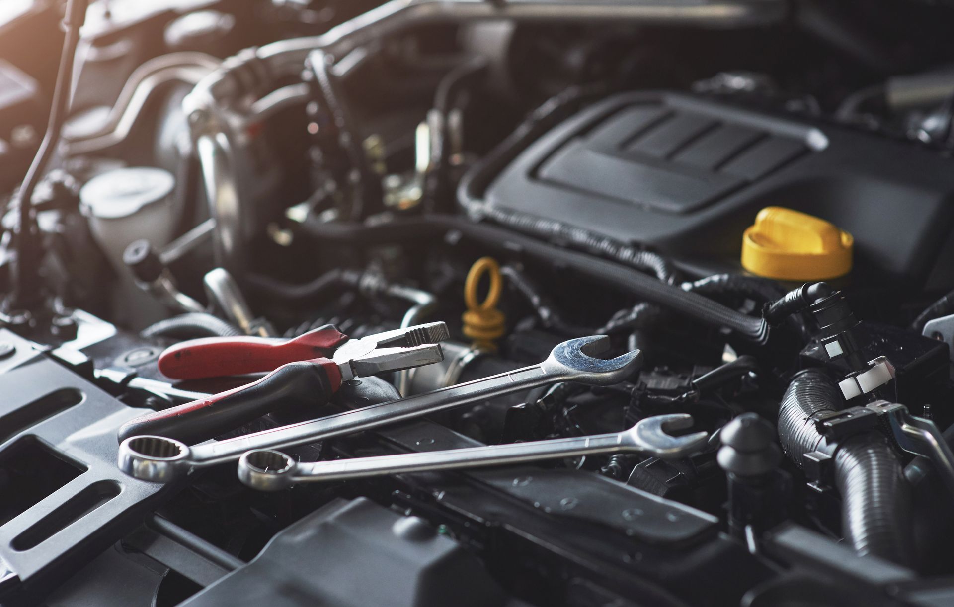 Open car engine with wrenches and tools laid across the engine.