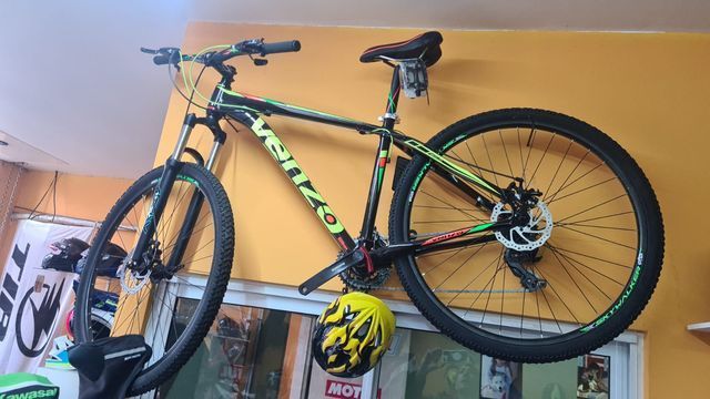 Una bicicleta está colgada en una pared junto a un casco.