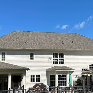 A two-story white house with light grey shingles and a blue sky in the background.