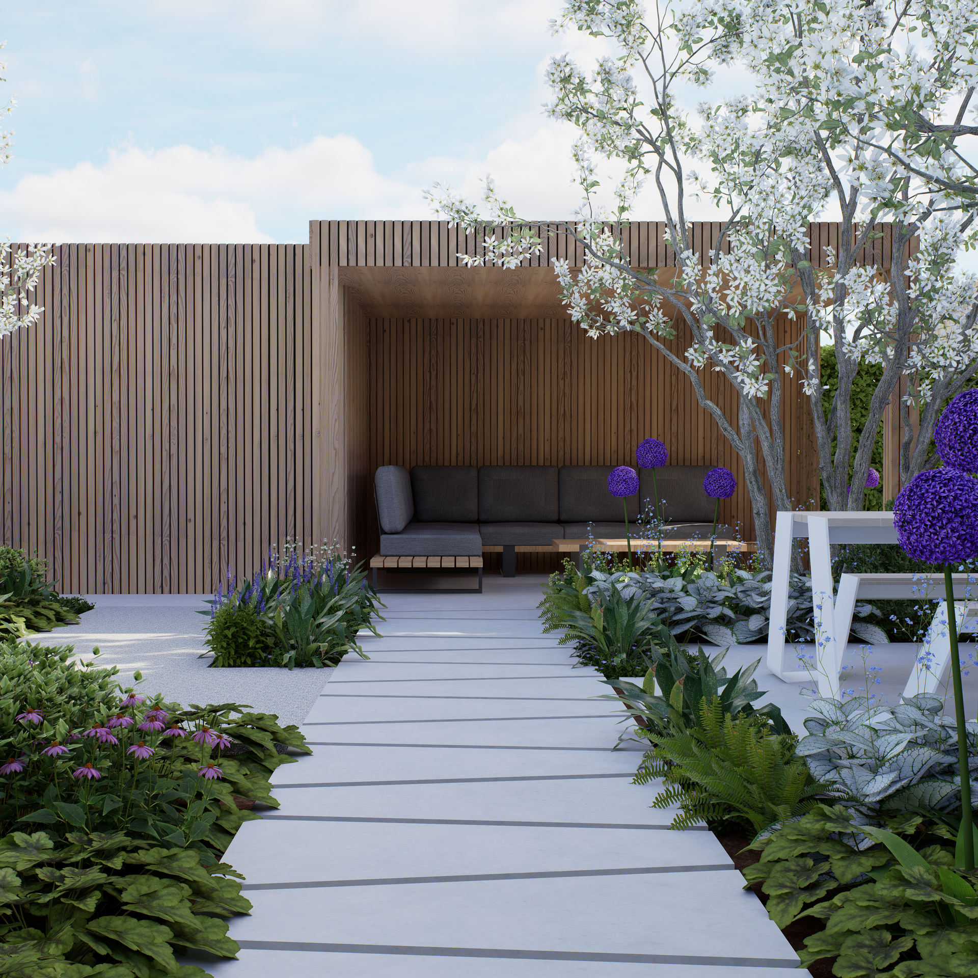 Pathway leads to a wooden structure with seating, surrounded by a garden with white and purple flowers, trees, and greenery.
