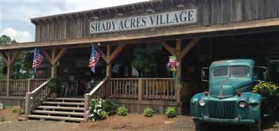 Shady Acres Village front entrance with sign, shrubbery, and American flag