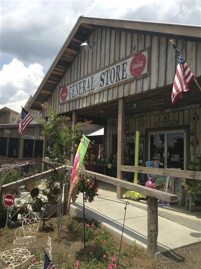 General store front entrance with lawn decorations and 2 American flags