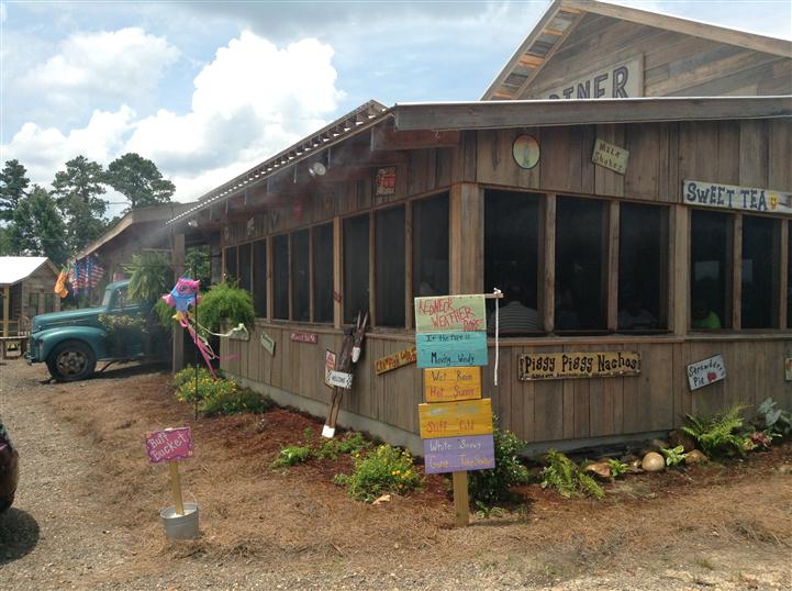 Outside of a establishment with sign lawn decor and people sitting within the establishment