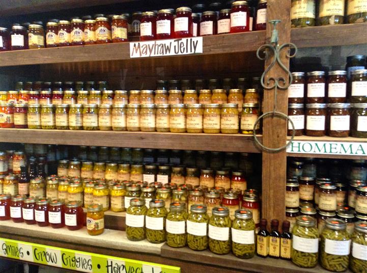 Jarred Mayhaw Jelly with other jarred delicacies underneath it on the shelf