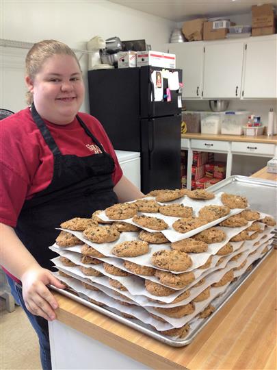 Baker holding freshly baked cookies on a table