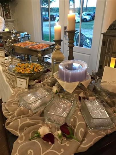 Broccoli salad along with other foods on a table with utensils and plates