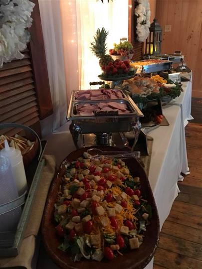Salad on a table along with meats and fruits