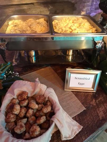 Scrambled eggs in a stove with sausages in a basket beneath it.