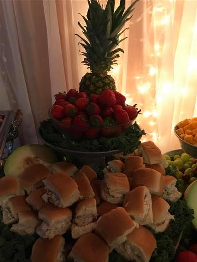 Sandwiches topped on fruits with strawberries, pineapples, honey dew, and grapes