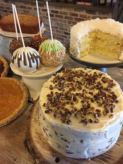 Dipped apples on a stick next to multiple cakes and pies