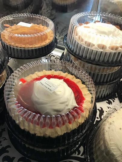 Multiple pies in plastic casing on a display for sale