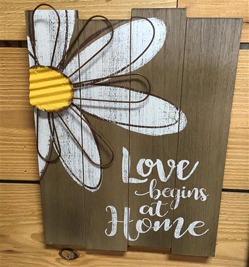 Sign with a flower and a wooden backdrop that reads 