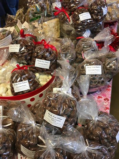 Bagged and assorted chocolate candies within a basket on a table with hearts