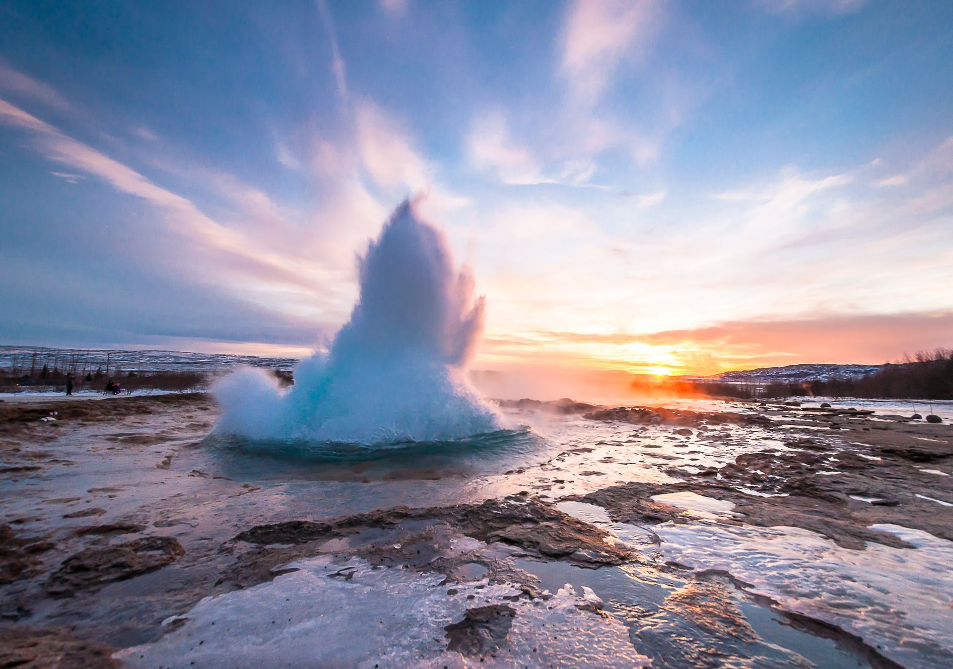 Geysir erupting in the South Coast of Iceland on the Golden Circle trail with the backdrop of the winter sun.
