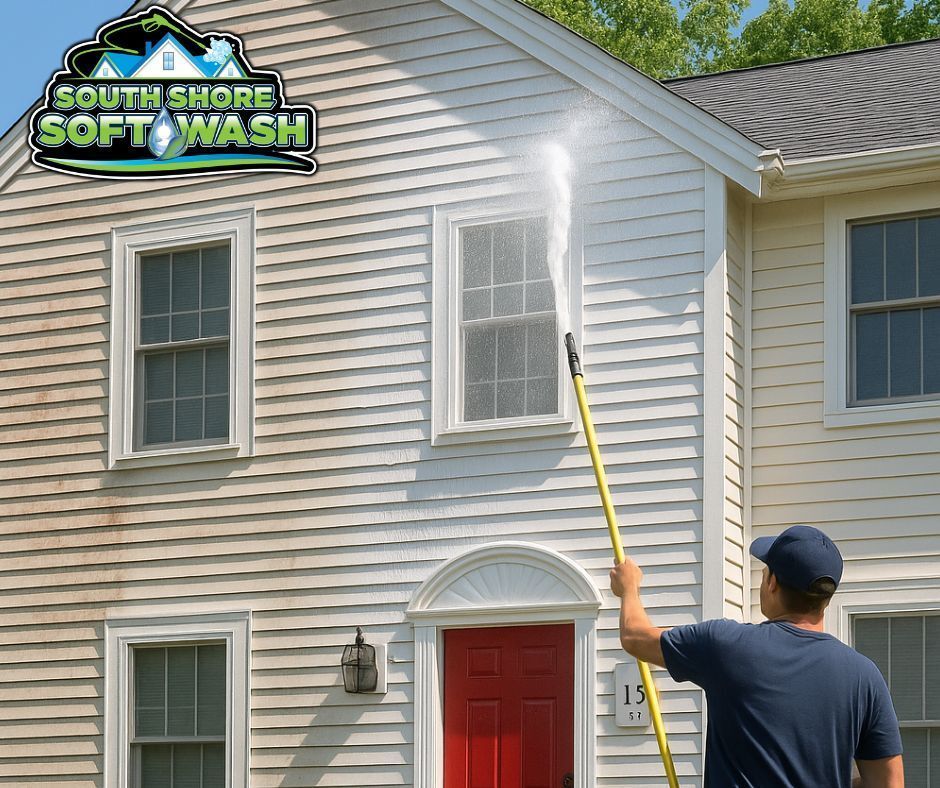 A man is cleaning the side of a house with a high pressure washer.